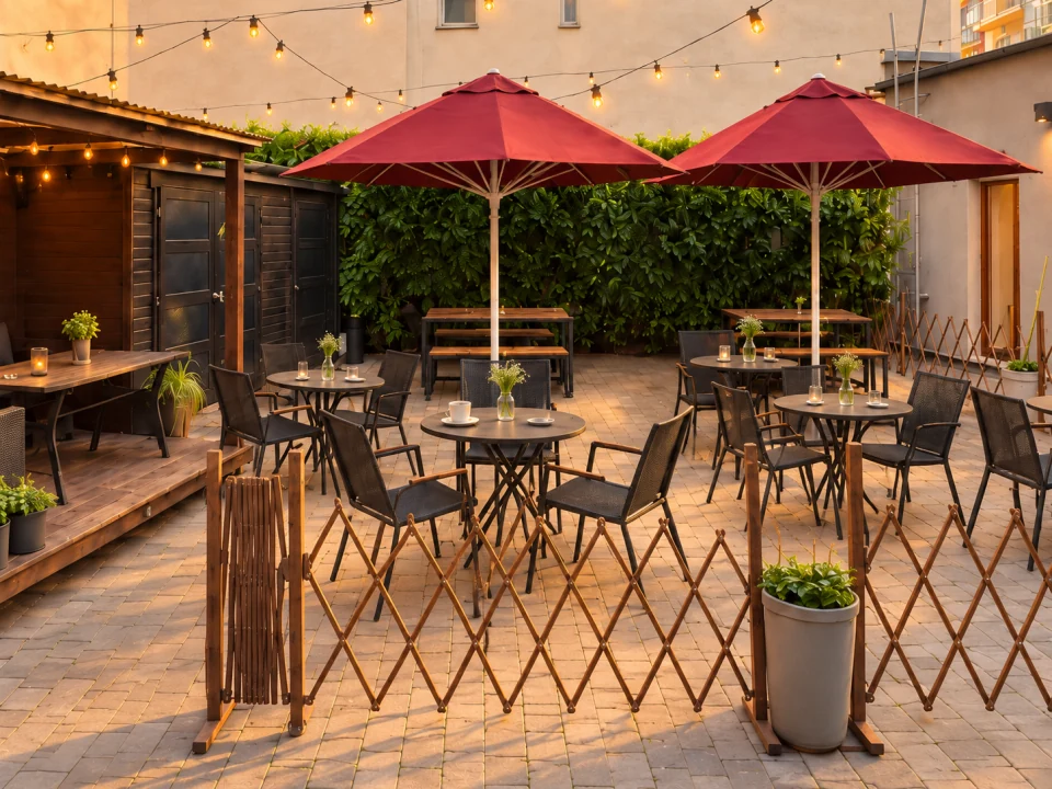 Vinohradská zahrádka s bistro stolky, červenými slunečníky a rozsvícenými řetězy